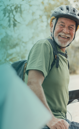 Oudere man op fiets met een fietshelm op.
